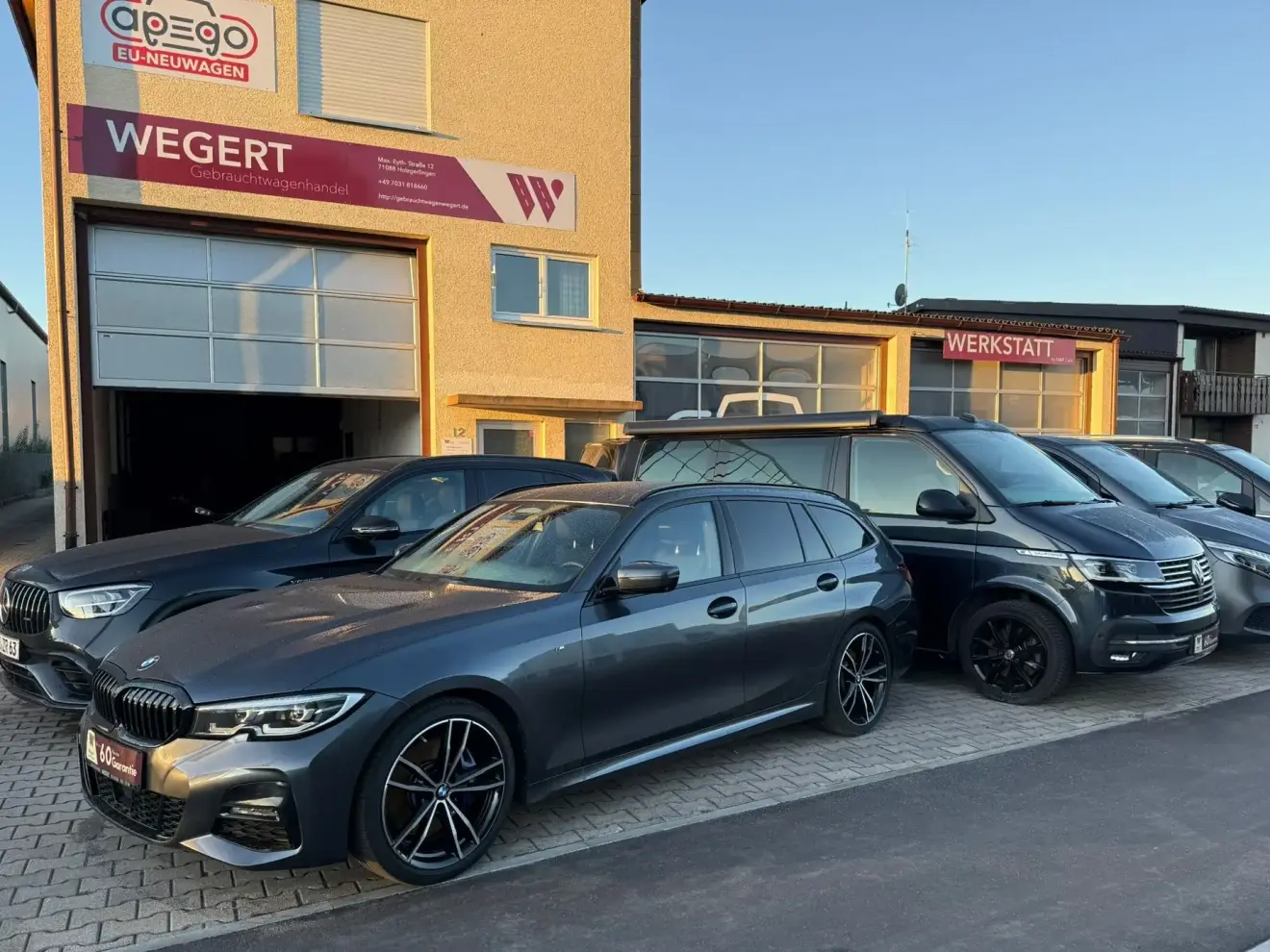 Betriebsgebäude von Gebrauchtwagenhandel Wegert in Holzgerlingen in der Abendsonne, davor Fahrzeuge auf dem Hof